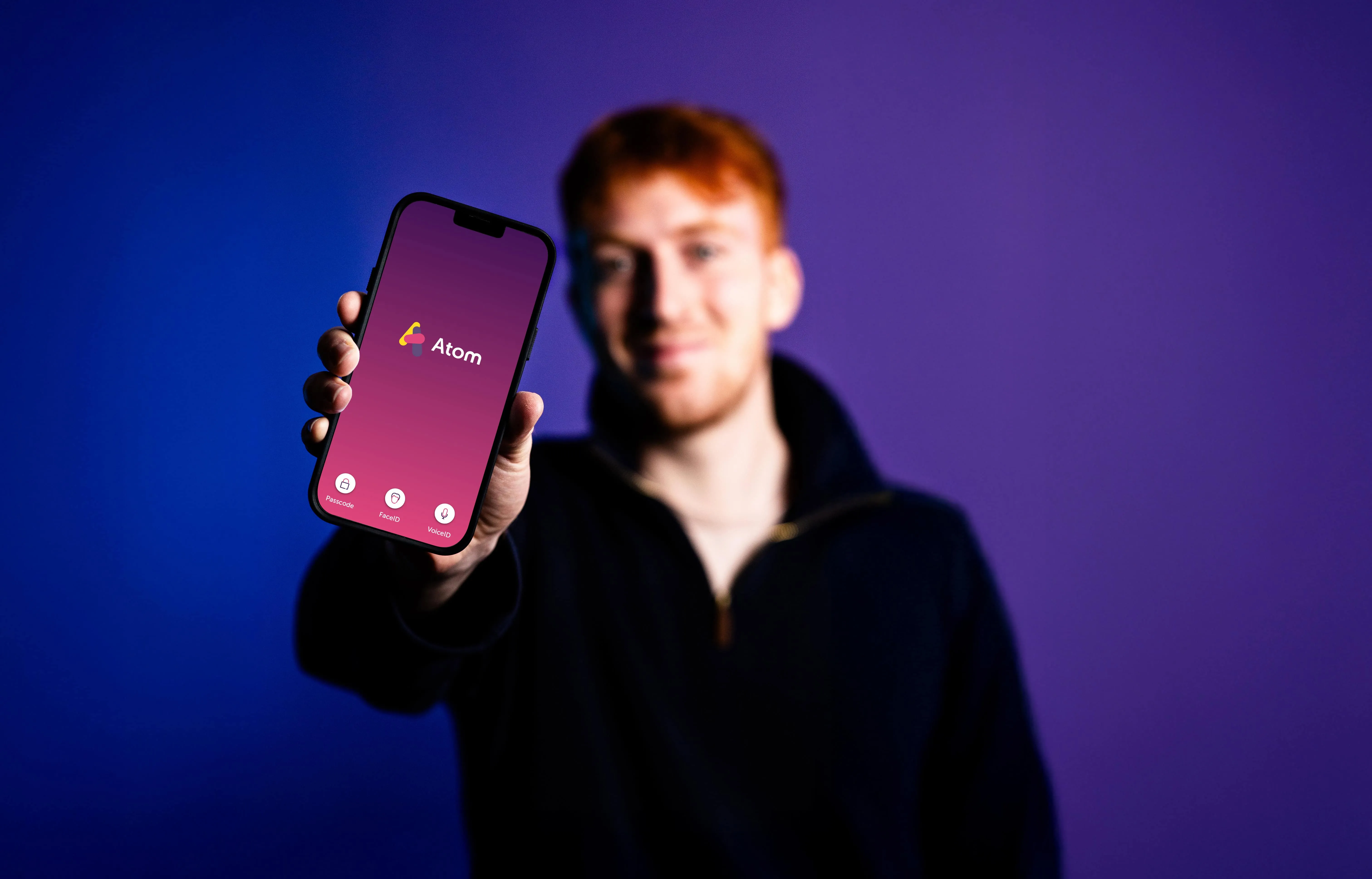 A man holding a phone with the Atom Bank app on display