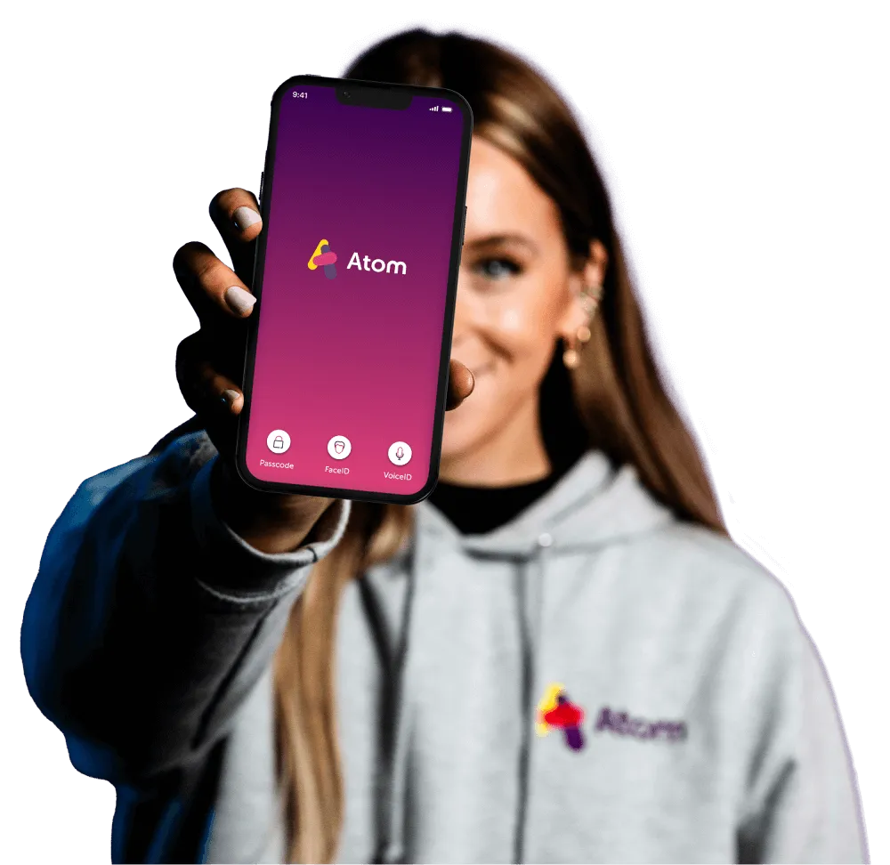 A woman holding a phone out showing the atom app homepage