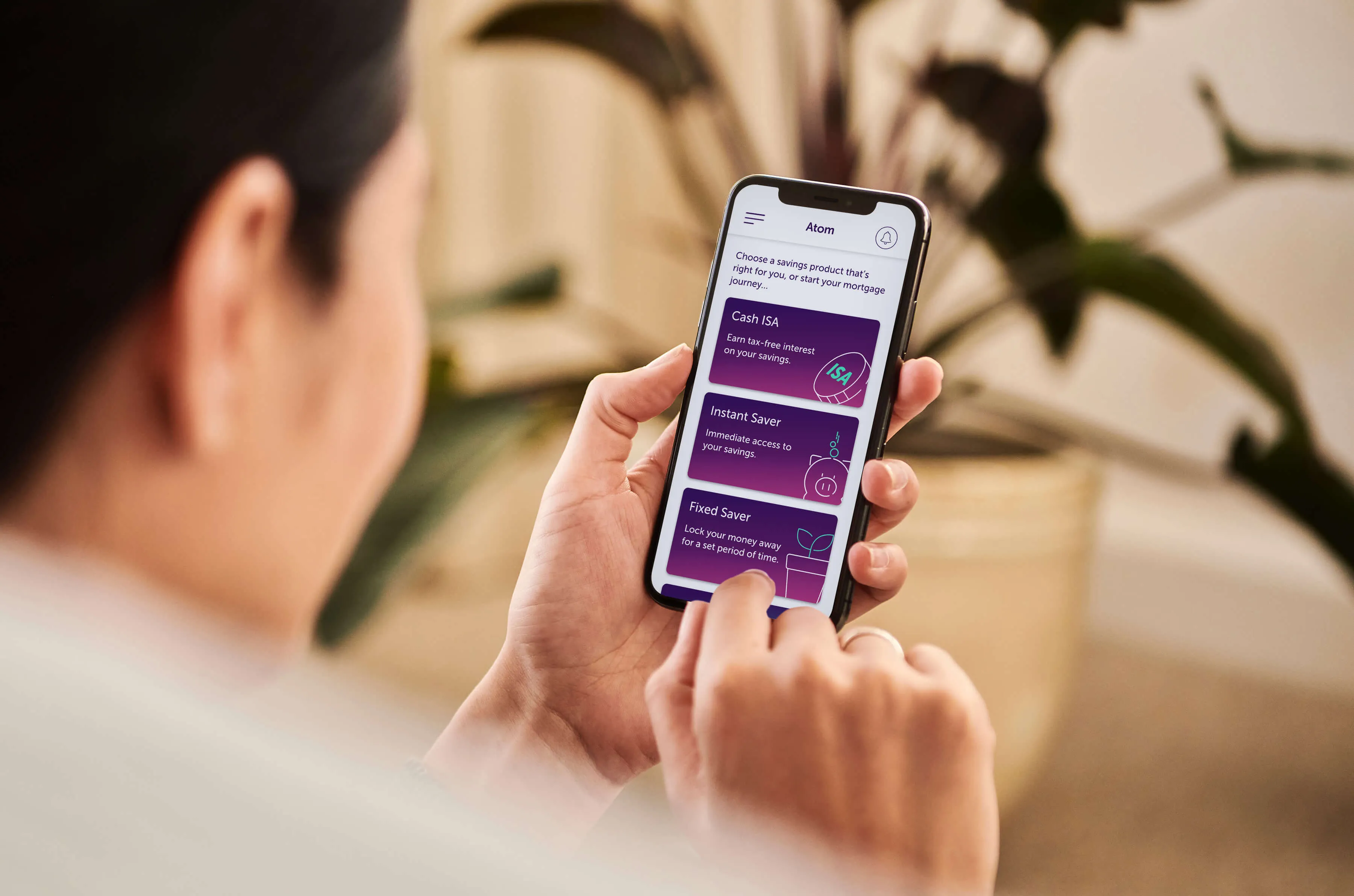 Someone holding a phone looking at the atom bank app products page