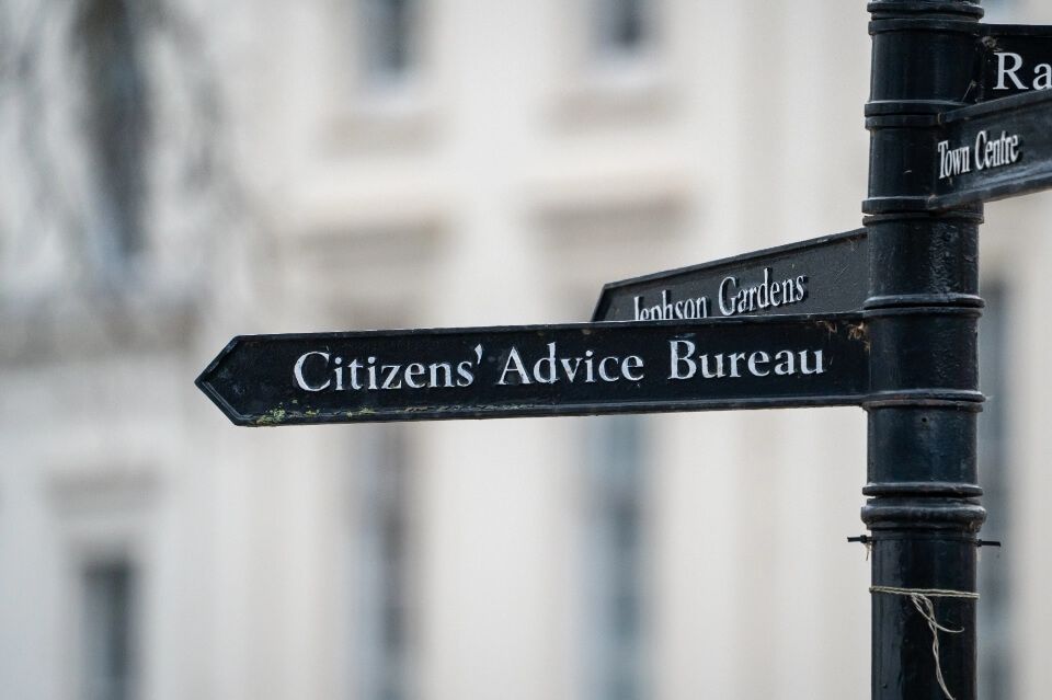 A signpost with a sign directing to Citizens' Advice Bureau
