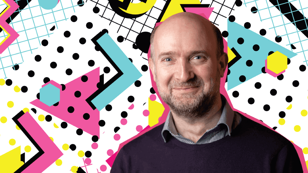 Atom bank CCO, Ed Twiddy, smiling with a retro 90s style background of blue, pink and yellow shapes