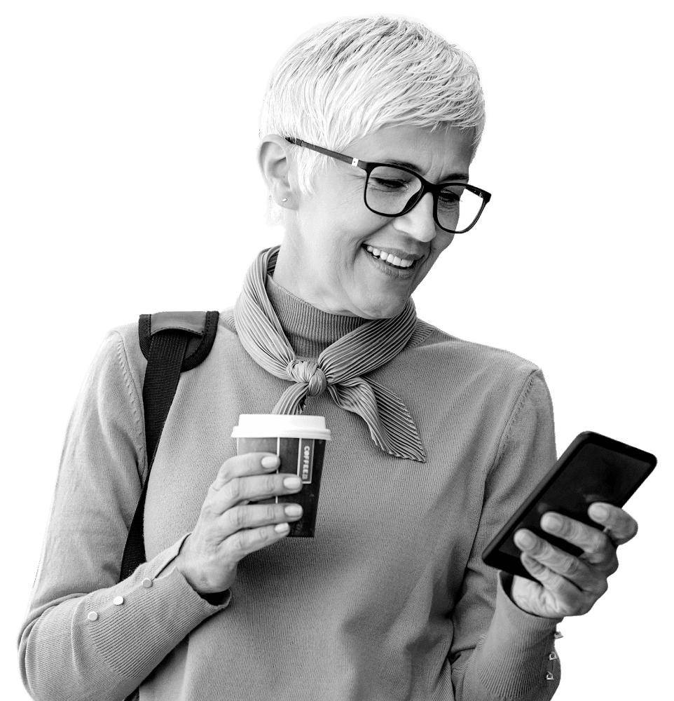 Older woman happily checking her Atom Fixed Saver on her mobile phone whilst holding a coffee