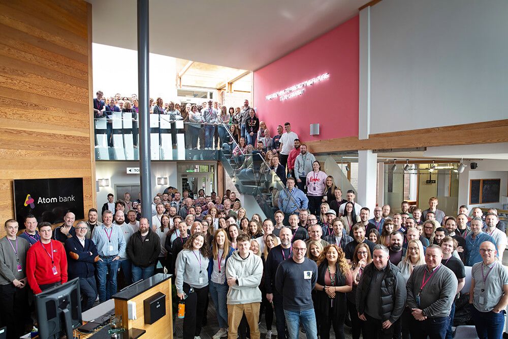 Everyone at Atom bank HQ stood in the lobby looking up and smiling to the camera