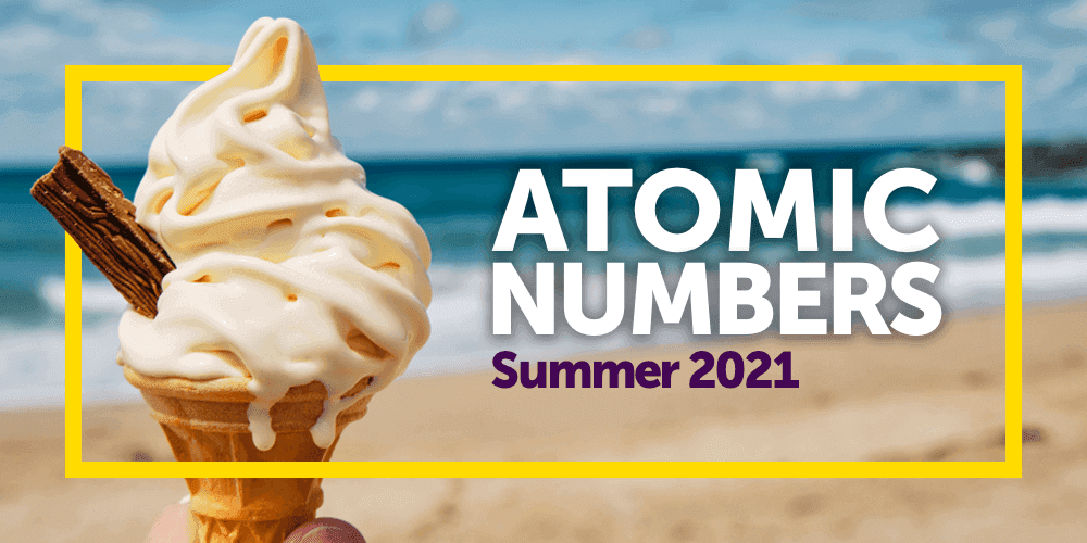 Someone holding a soft serve ice cream cone with a flake at the beach. The copy Atomic numbers Summer 2021