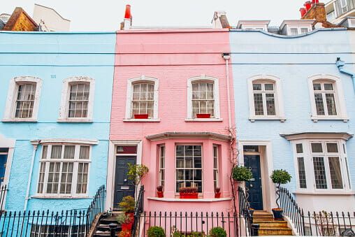 Three brightly coloured terraced houses with large bay windows and steps up to the front door