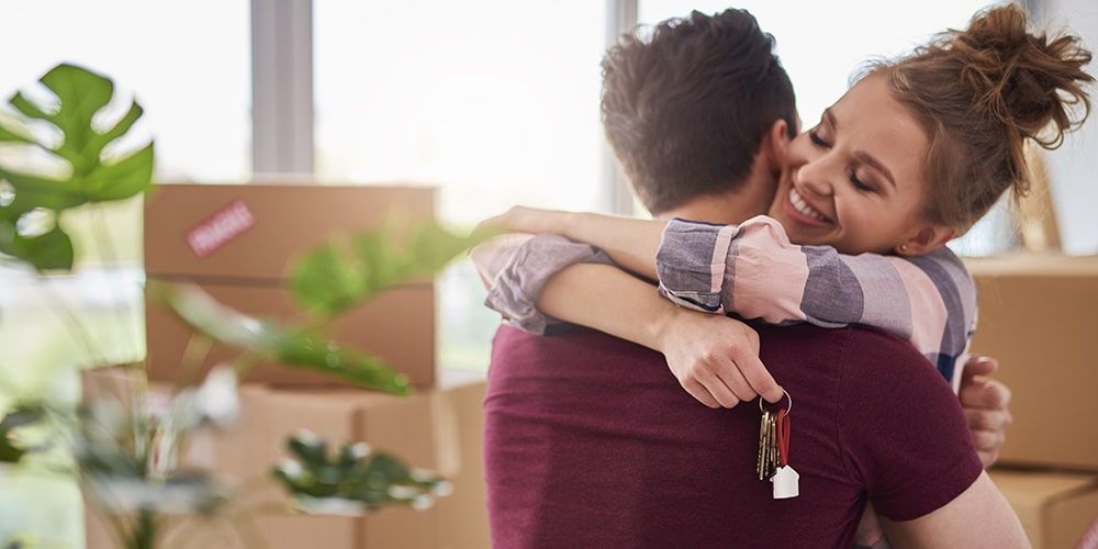 A couple sharing an embrace while one of them is holding a set of house keys