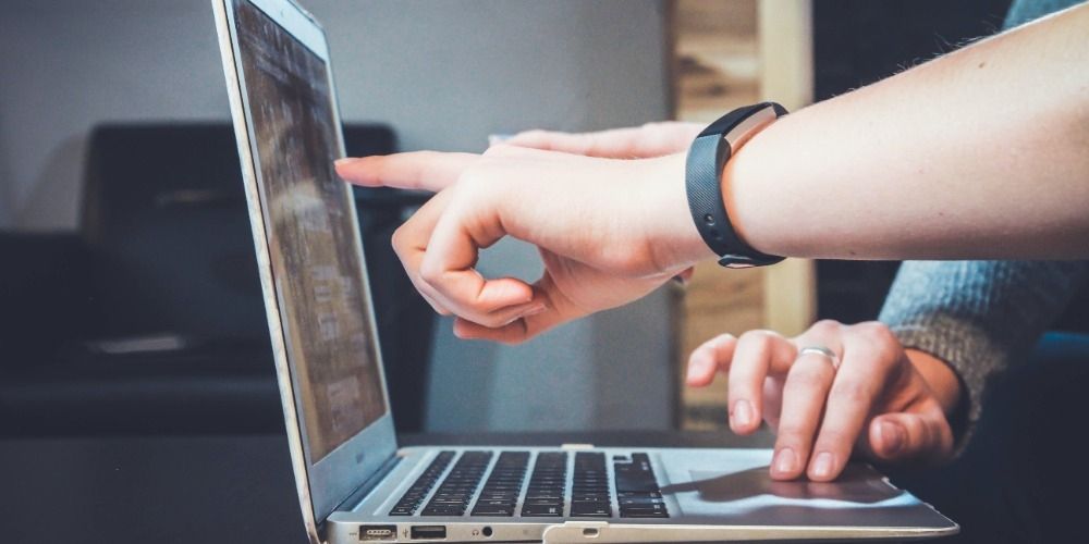 Two people pointing at a laptop