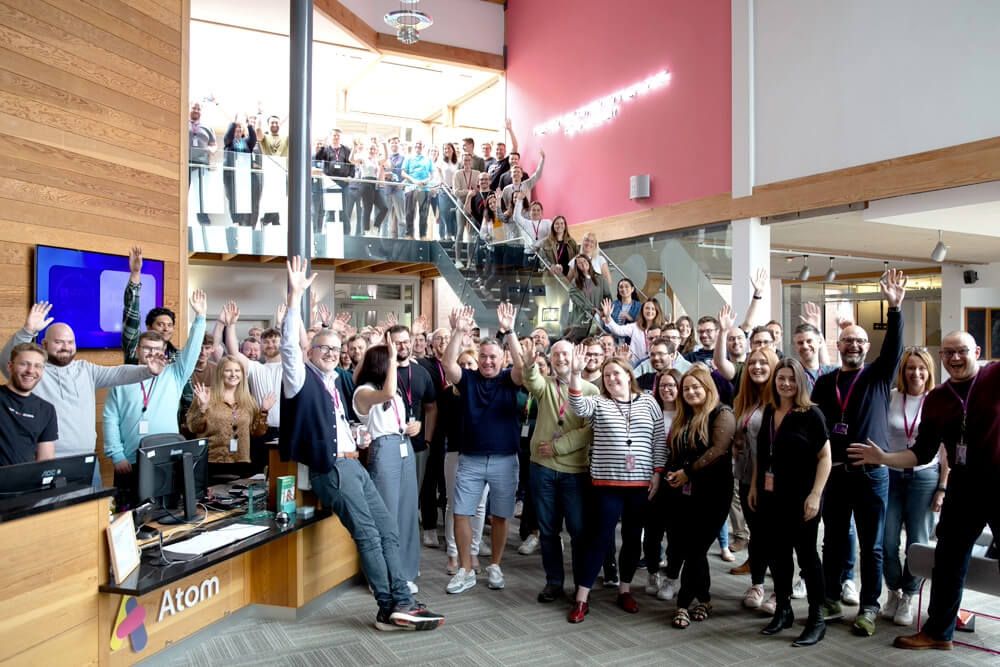 Everyone at Atom bank HQ stood in the lobby smiling to the camera