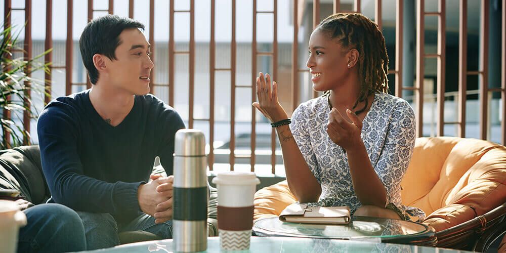 Two people sitting down at a coffee table and talking