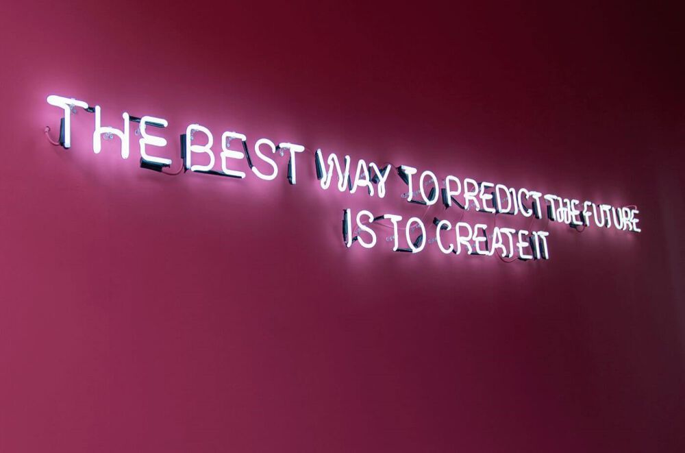 A neon sign featured in the Atom bank lobby on the pink wall. It reads The Best way to predict the future is to create it