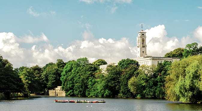 River surrounded by full trees with some rowing boats in the middle of the water