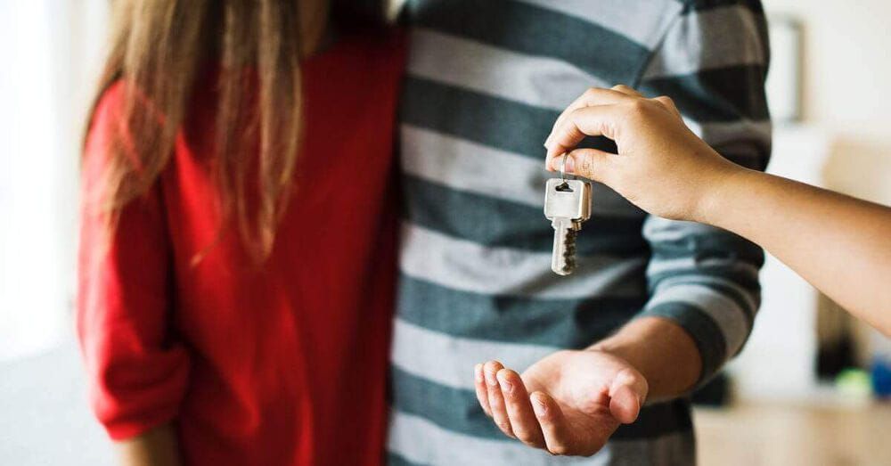 Someone handing over a set of keys to a young couple