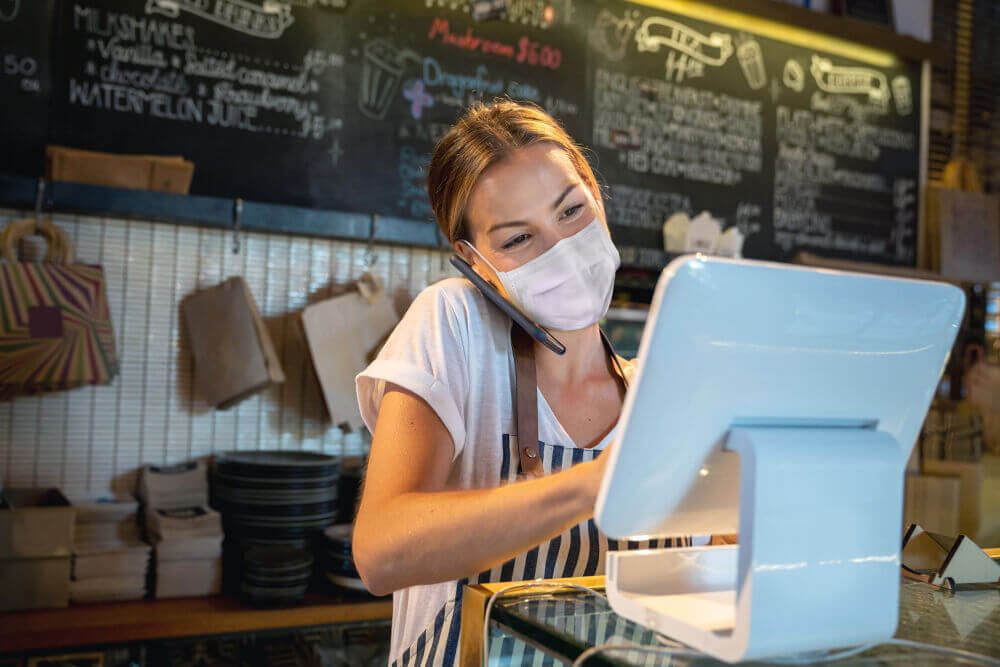 Small business owner at their point of sale system wearing a face mask
