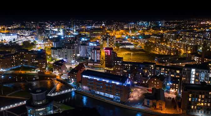 Leeds city centre at night, bright lights shining into the dark evening