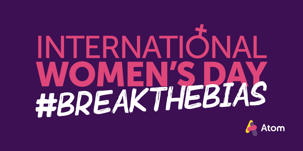 On a purple background, the copy International Woman's Day #BreaktheBias sits in pink and white. The O of Interational has been replaced with the symbol for women