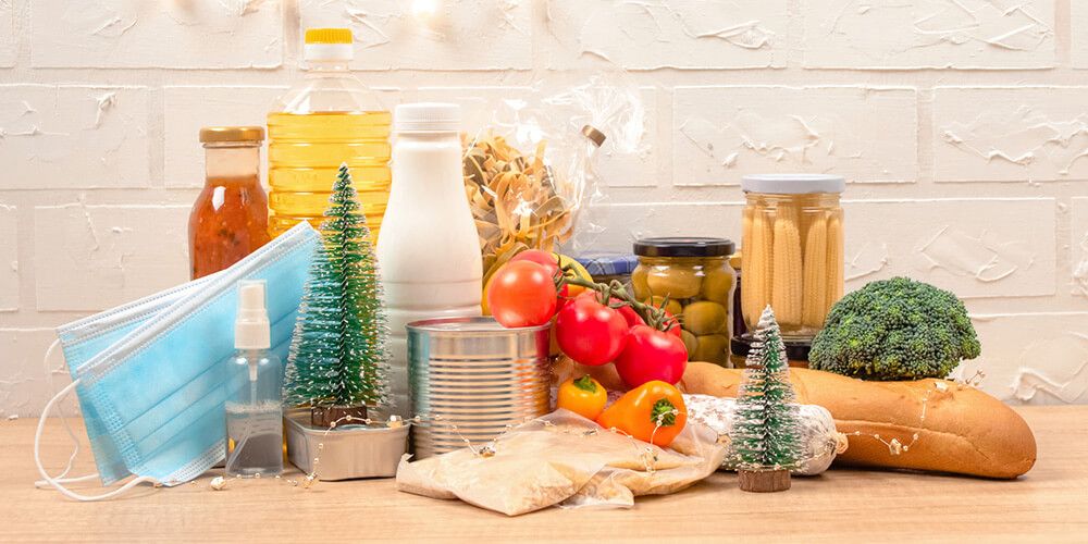A kitchen bench of canned, jarred and fresh foods on display with facemasks and sanitizer spray