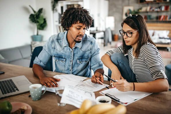 Man and woman looking through paper work. Both look very serious, man is pointing to something on the page