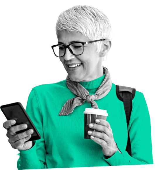 Older woman happily checking her Atom Fixed Saver on her mobile phone whilst holding a coffee